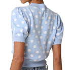 a woman wearing a blue and white polka dot short sleeve puff sleeve cardigan on white background