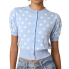 a woman wearing a blue and white polka dot short sleeve puff sleeve cardigan on white background