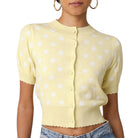 Yellow polka dot cardigan worn by a person on a white background
