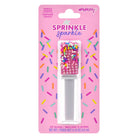 A packaged lip gloss bottle labeled 'Sprinkle sparkle' on a pink backing card. The gloss container is filled with pink rhinestones and small multicolored sprinkles, and the card includes the brand name Poppy's.