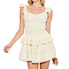 Woman wearing a light yellow ruffled dress on a white background