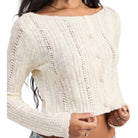 Cream-colored knitted sweater worn by a person on a white background
