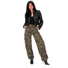 A woman modeling a black faux-leather cropped jacket and olive green camouflage cargo pants with black high-heeled boots, set against a plain white background.