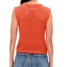Person wearing an orange sleeveless knitted top and blue jeans on a white background