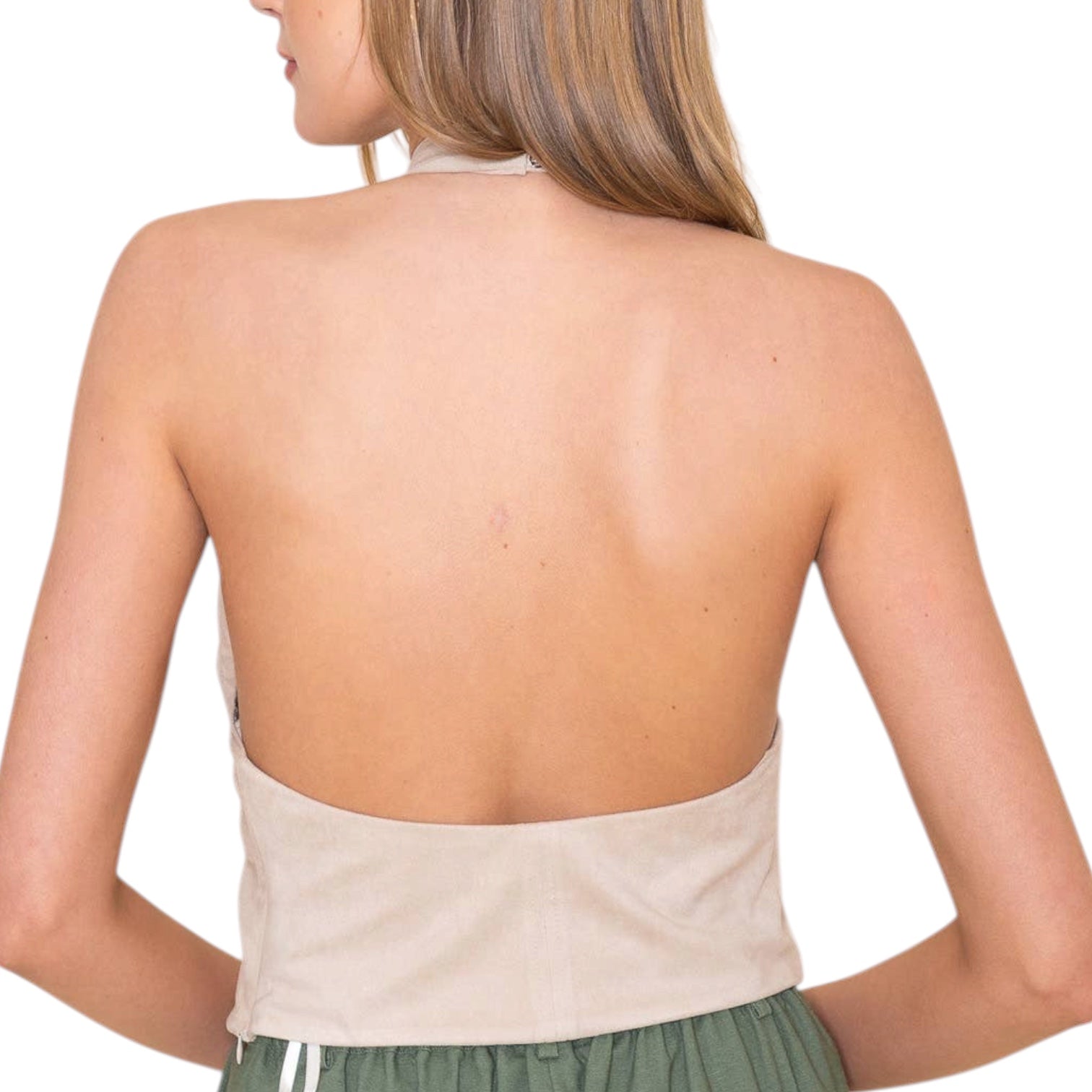 Woman wearing a beige open-back top with green shorts on a white background
