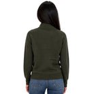 A woman viewed from the back wearing an olive green mock neck sweater and blue jeans against a plain white background.