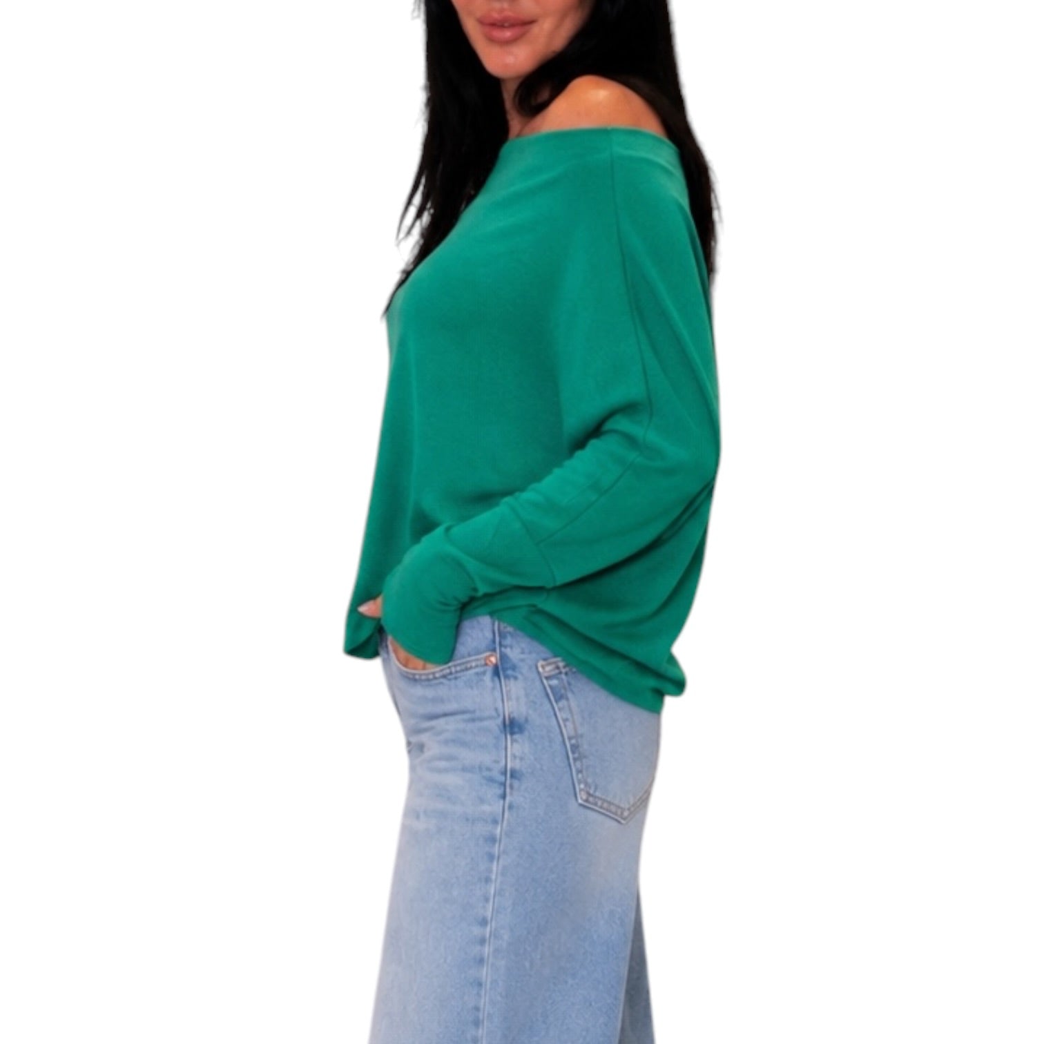 A woman wearing a bright green off-the-shoulder long-sleeve top and light blue jeans, shown from the side against a plain white background.