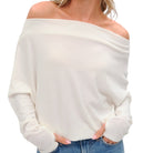 White off-shoulder sweater worn by a person on a white background