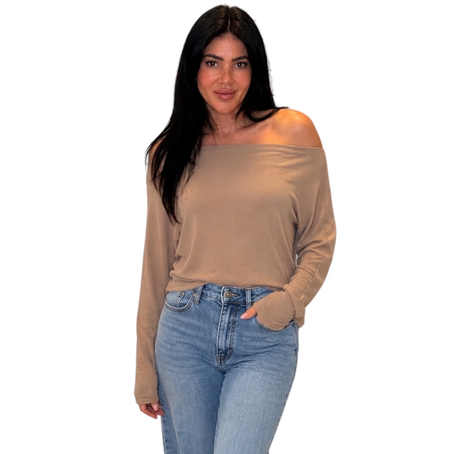 A woman modeling a beige off-the-shoulder long-sleeve top paired with light-wash blue jeans against a plain white background.