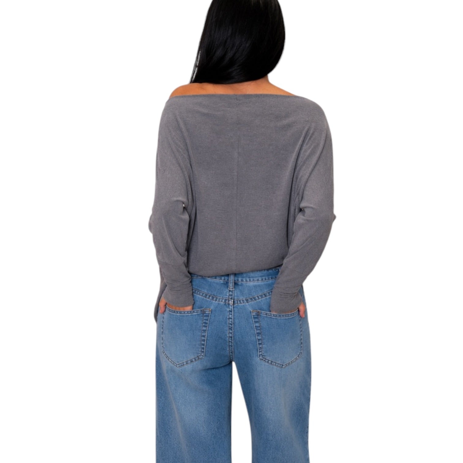 A woman shown from the back wearing a gray off-the-shoulder long-sleeve top and blue jeans against a plain white background.