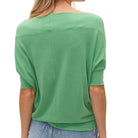 Green top worn by a person on a white background