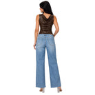 A woman shown from the back wearing a dark brown faux-leather cowl-neck sleeveless top and light-wash wide-leg blue jeans, standing against a plain white background.