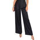 A woman modeling a black satin halter-neck top and matching wide-leg pants set against a plain white background.
