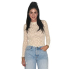 A woman modeling a beige lace long-sleeve mock neck top paired with light-wash blue jeans, set against a plain white background.