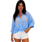 Woman wearing a light blue cover-up with palm tree designs on a white background