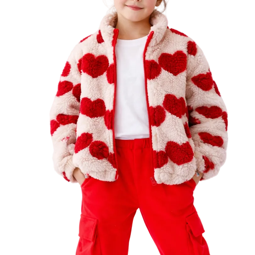 Child wearing a heart-patterned jacket and red pants on a white background