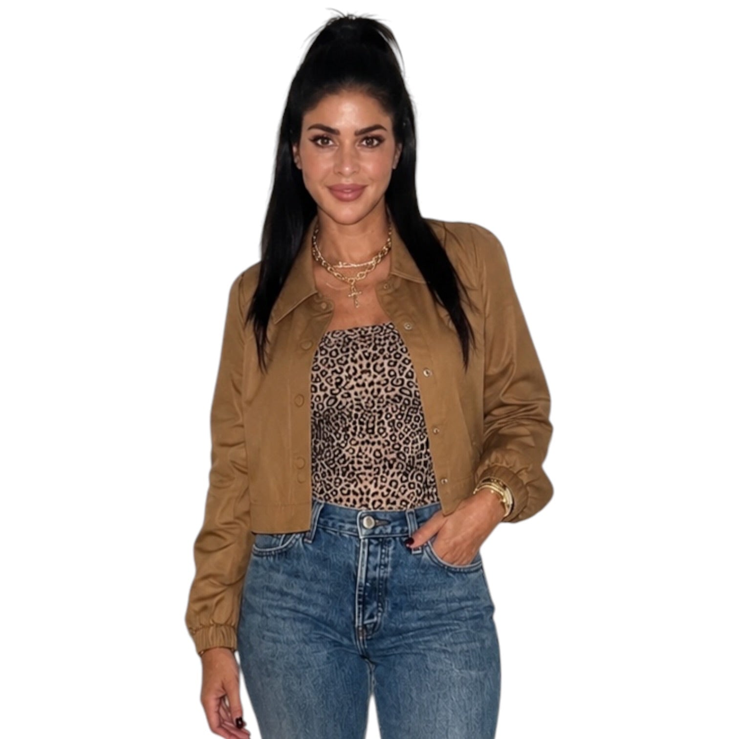 A woman modeling a cropped tan jacket over a leopard-print top and blue jeans, standing against a plain white background.