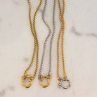 Three gold and silver chain necklaces on a marble surface