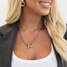 Woman wearing a gold pendant necklace with a plain background