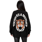 A woman viewed from the back wearing a black knit sweater with a large tiger face graphic and the words 'TOUGH AS A MOTHER' in white around the upper back.