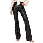 A model wearing black faux-leather flare pants paired with a cream polka-dot blouse and clear high-heeled sandals, shown from the waist down on a white background.