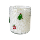 A holiday-themed glass jar candle with white wax and a textured, pebble-like pattern. The clear glass features decorative green and red glass ornaments shaped like a Christmas tree and a gift box.