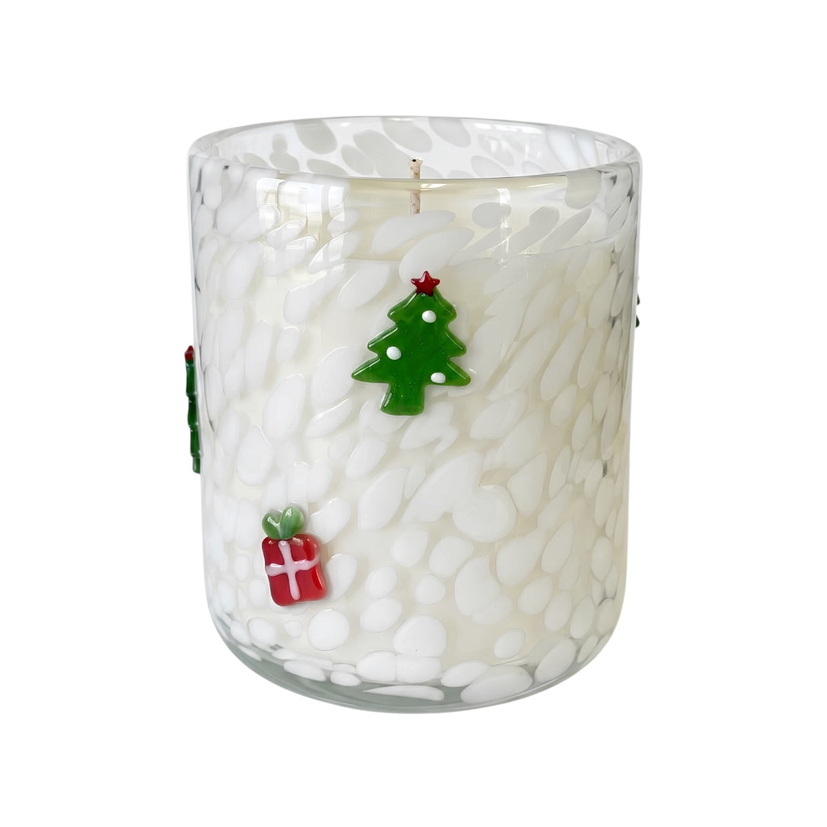 A holiday-themed glass jar candle with white wax and a textured, pebble-like pattern. The clear glass features decorative green and red glass ornaments shaped like a Christmas tree and a gift box.
