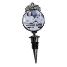 A novelty wine bottle stopper featuring a circular emblem with a black-and-white photo of two women and the text 'GIRLFRIENDS MATTER,' topped with a silver floral crown design and a metal spike base.