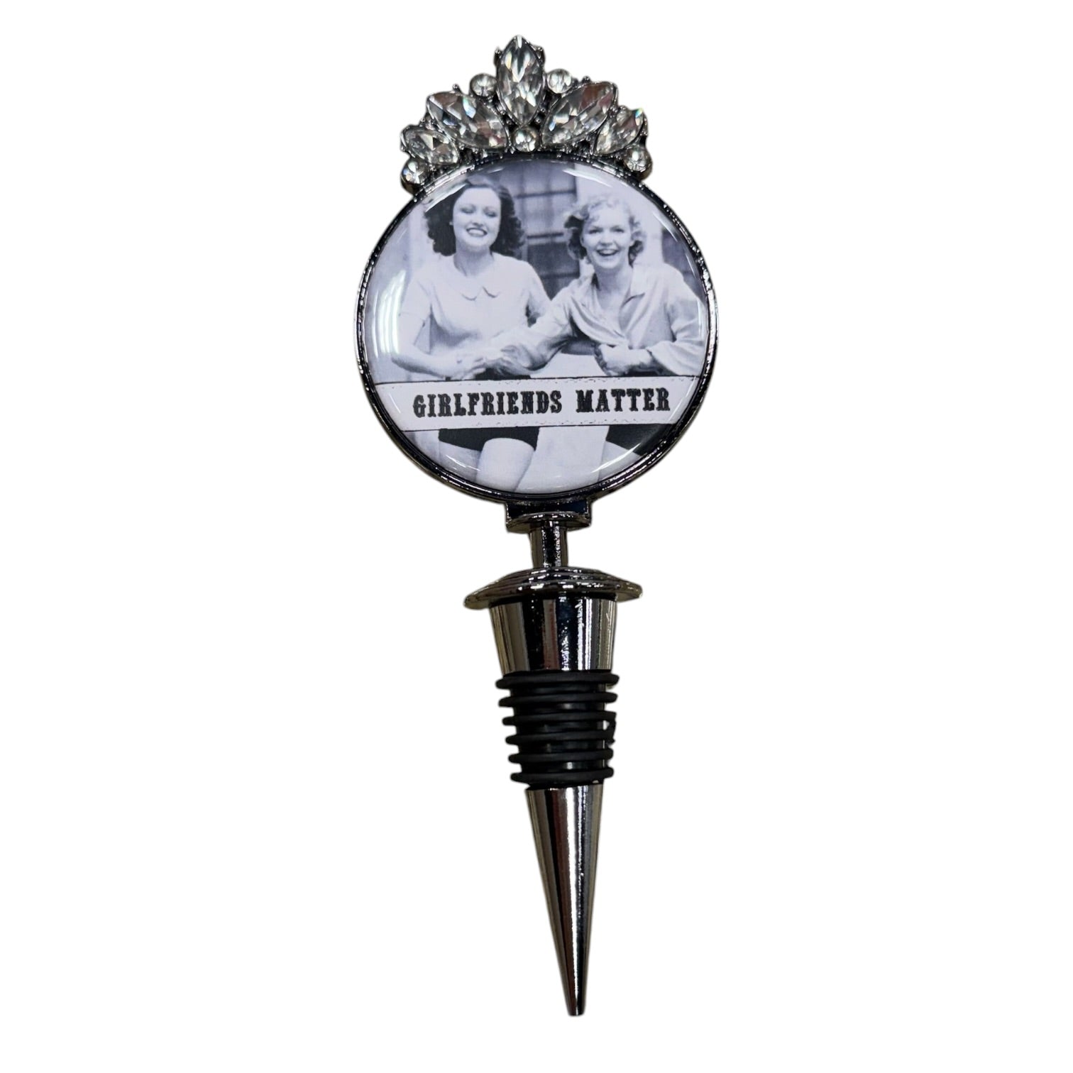 A novelty wine bottle stopper featuring a circular emblem with a black-and-white photo of two women and the text 'GIRLFRIENDS MATTER,' topped with a silver floral crown design and a metal spike base.