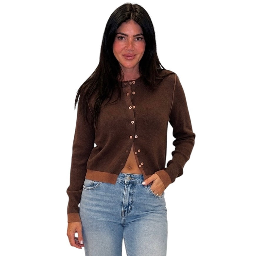 A woman modeling a cropped brown knit cardigan with a button-down front, paired with light blue jeans, against a plain white background.