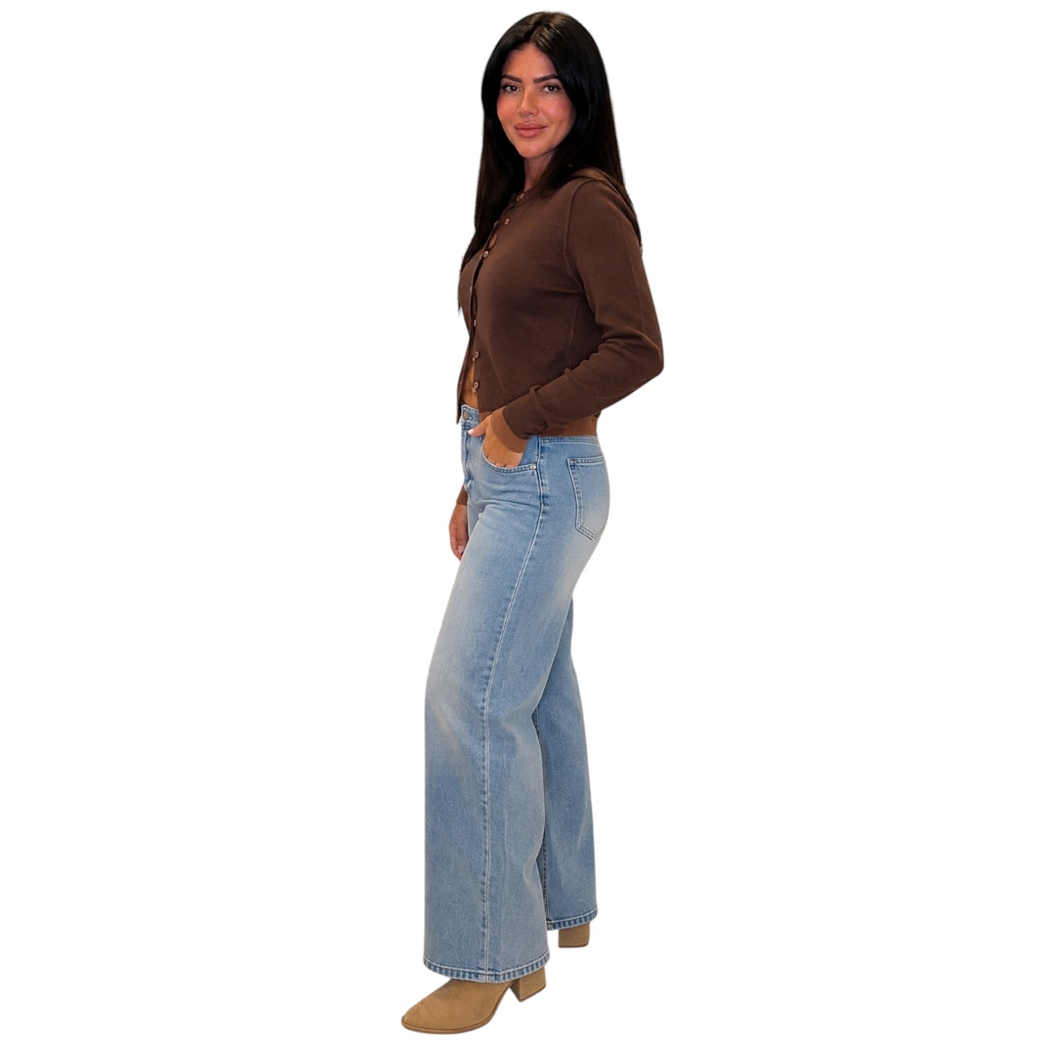 A woman modeling a brown long-sleeve cropped top and light-wash blue flare jeans against a plain white background.
