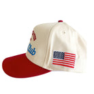 Cap with red brim, beige top, and American flag patch on a white background