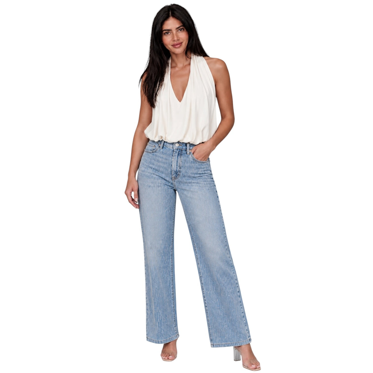 A woman modeling a white sleeveless halter top and light-wash wide-leg blue jeans against a plain white background.