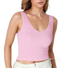 Woman wearing a pink ribbed tank top against a white background