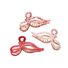 Three pink and gold hair clips on a white background
