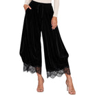 Black velvet harem-style pants with a lace hem, shown on a model wearing a cream long-sleeve top and clear high-heeled sandals against a white background.