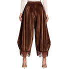 A model is shown from the back wearing brown velvet harem-style pants with lace trim at the hems, paired with a cream long-sleeve top and metallic high heels against a white background.