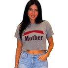 Woman wearing a gray t-shirt with 'Mother' printed on it against a white background