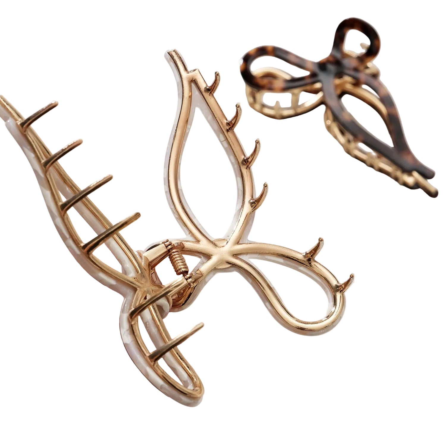 Gold hair clip held by a hand with another one in the background on a light surface.