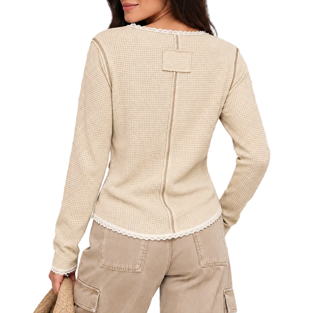 A woman shown from the back wearing a beige textured knit long-sleeve top with a decorative back detail and matching beige pants, against a checkered transparency-style background.