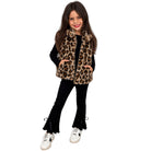 A young girl modeling a leopard fur vest against a white background 