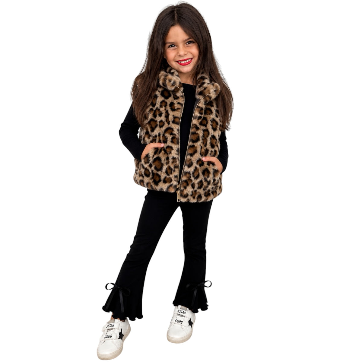 A young girl modeling a leopard fur vest against a white background 