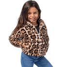 A young girl smiling while wearing a fuzzy leopard-print fleece jacket with a white zipper, paired with blue jeans, against a solid white background.