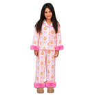 A young girl stands against a plain white background wearing a two-piece pajama set. The pajamas are white with an all-over orange pumpkin print and pink bows, finished with bright pink faux-fur trim at the cuffs and ankles.
