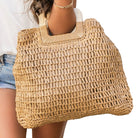 Woven straw bag held by a person on a white background