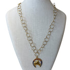 A gold-tone chain necklace with a horse-head pendant, displayed on a cream fabric-covered jewelry bust against a white background.