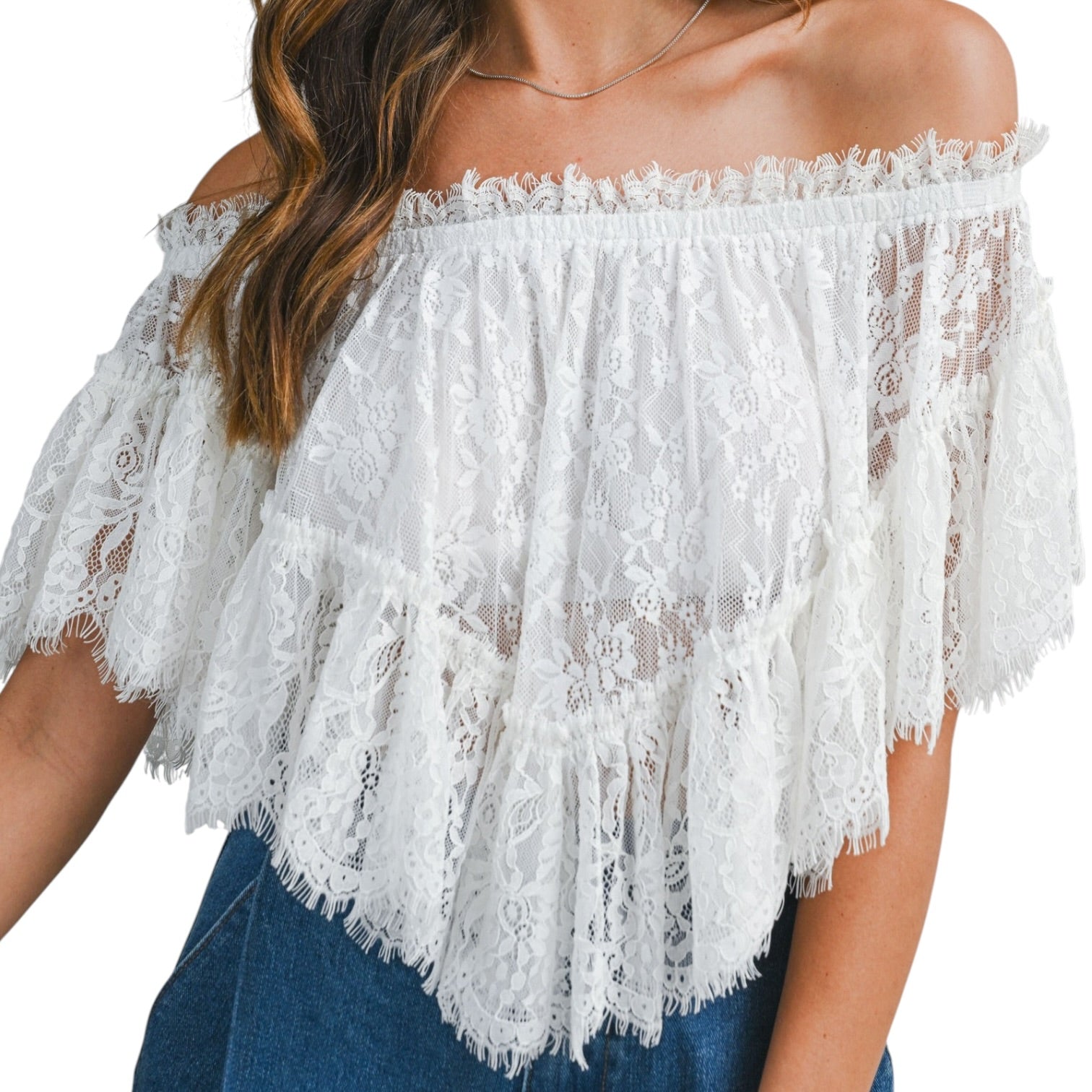 White lace off-shoulder top worn by a person on a white background