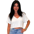 Woman wearing a white crop top and blue jeans on a white background