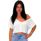 Woman wearing a white off-shoulder top and blue jeans on a white background