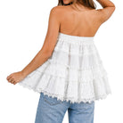 White strapless top with ruffled layers worn by a person on a white background